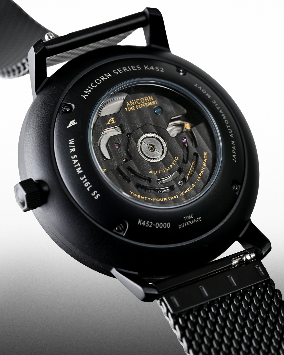 Anicorn K452 Nemesis caseback showing the automatic movement through the exhibition glass and black Milanese mesh bracelet.