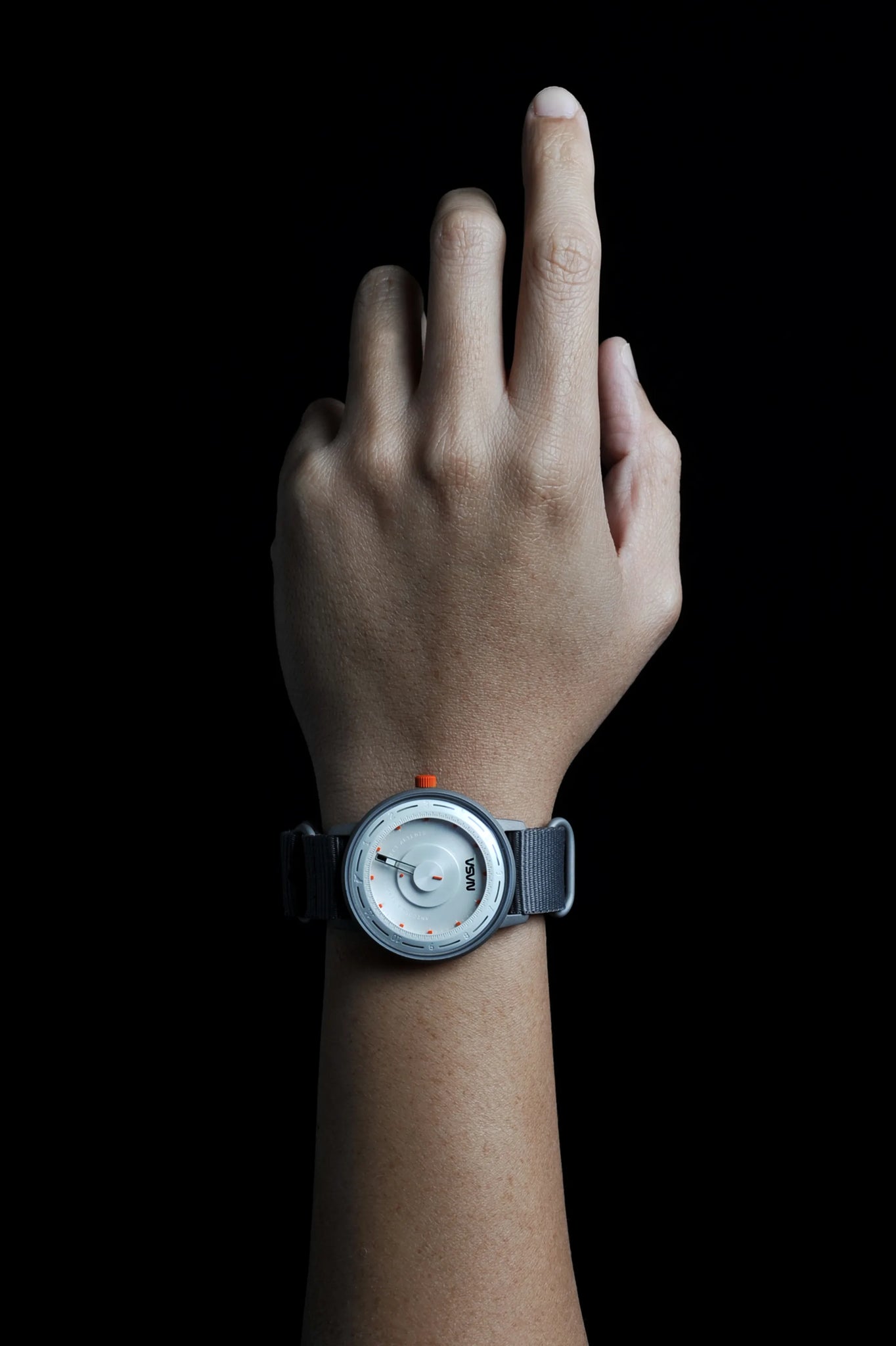 A hand wearing a timepiece called Artemis Time which is a timepiece to honor space missions, zero gravity as well as the salutation to the upcoming space expedition. Designed by Jeff Staple and ANICORN
