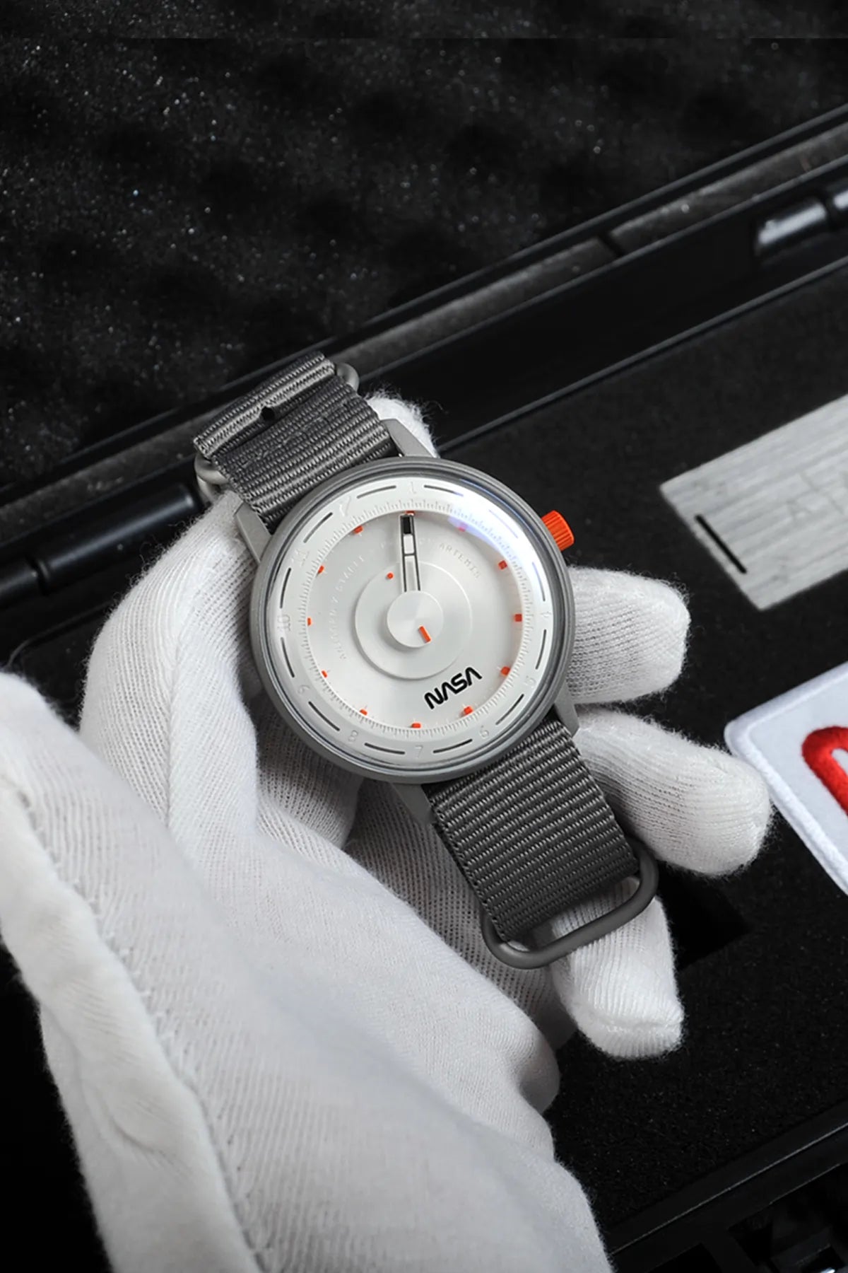 Artemis Time has a clean, minimal and sleek design, the gray color is inspired by the moon rock, with the orange highlights on the dial and crown recalling the “International Orange” applied on the spacesuit. 