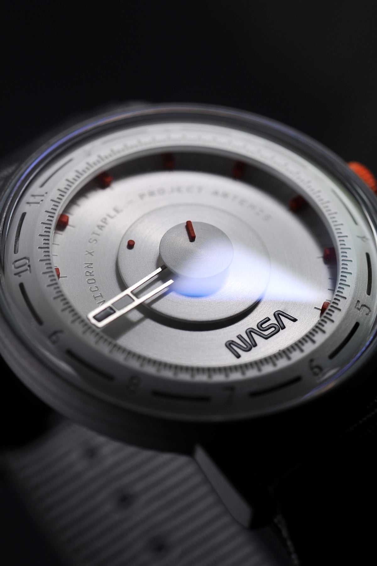 Artemis Time has a clean, minimal and sleek design, the gray color is inspired by the moon rock, with the orange highlights on the dial and crown recalling the “International Orange” applied on the spacesuit. 