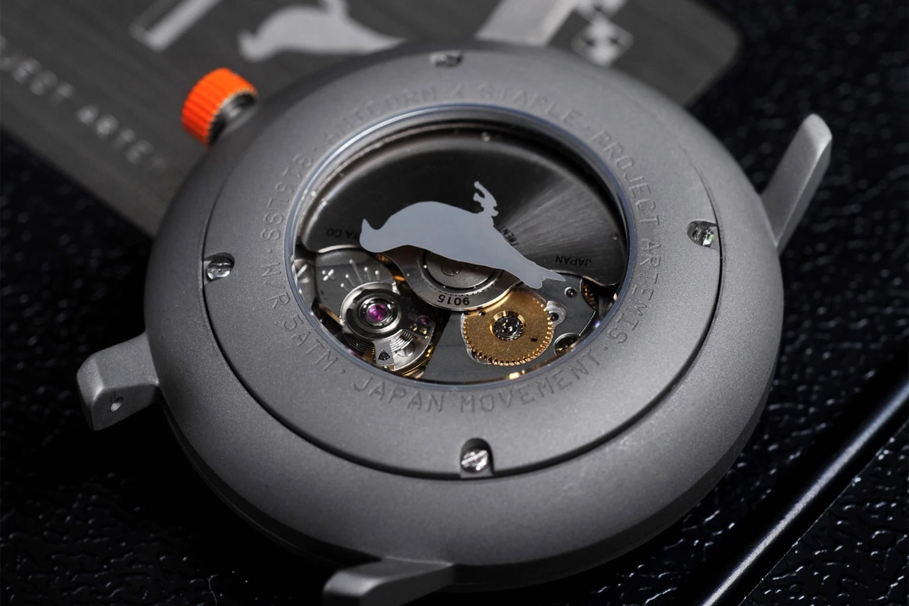 Artemis Time has a clean, minimal and sleek design, the gray color is inspired by the moon rock, with the orange highlights on the dial and crown recalling the “International Orange” applied on the spacesuit, back case