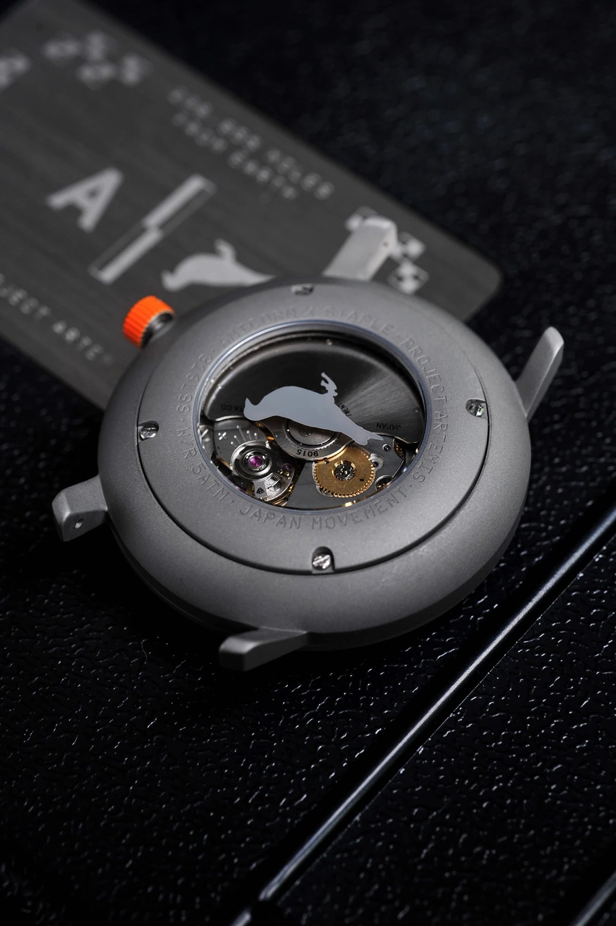 Artemis Time has a clean, minimal and sleek design, the gray color is inspired by the moon rock, with the orange highlights on the dial and crown recalling the “International Orange” applied on the spacesuit, back case