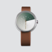 TTT#1 - Seoul - Hidden Time Watch - Olive. The front-view of the timepiece features a sleek green watch face, set against a background of rich brown straps, creating a unique and stylish look that is sure to turn heads.
