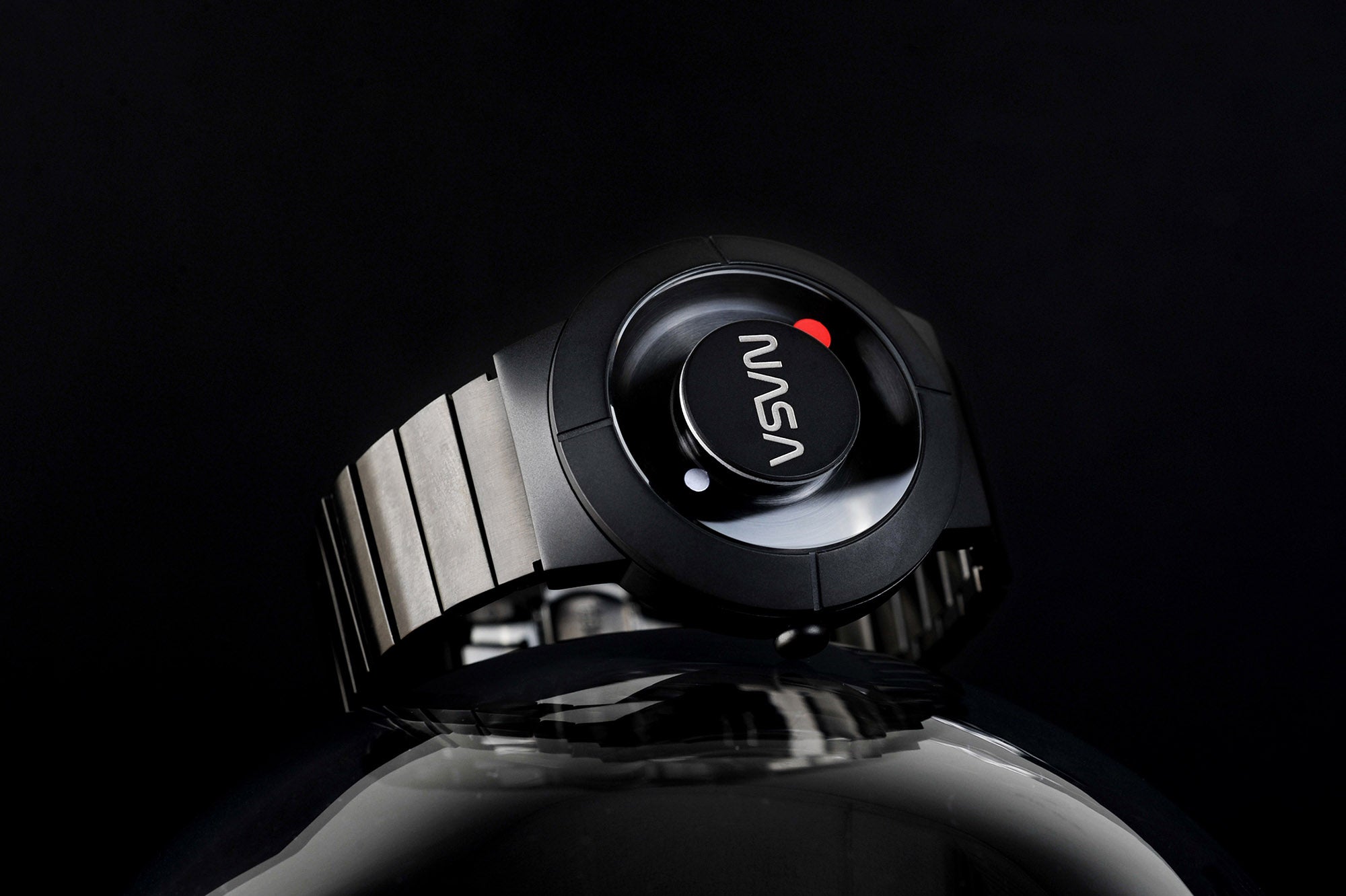 The Space Watch by Richard Danne featuring a black metallic bracelet and a unique dial with the NASA logo, against a dark backdrop.
