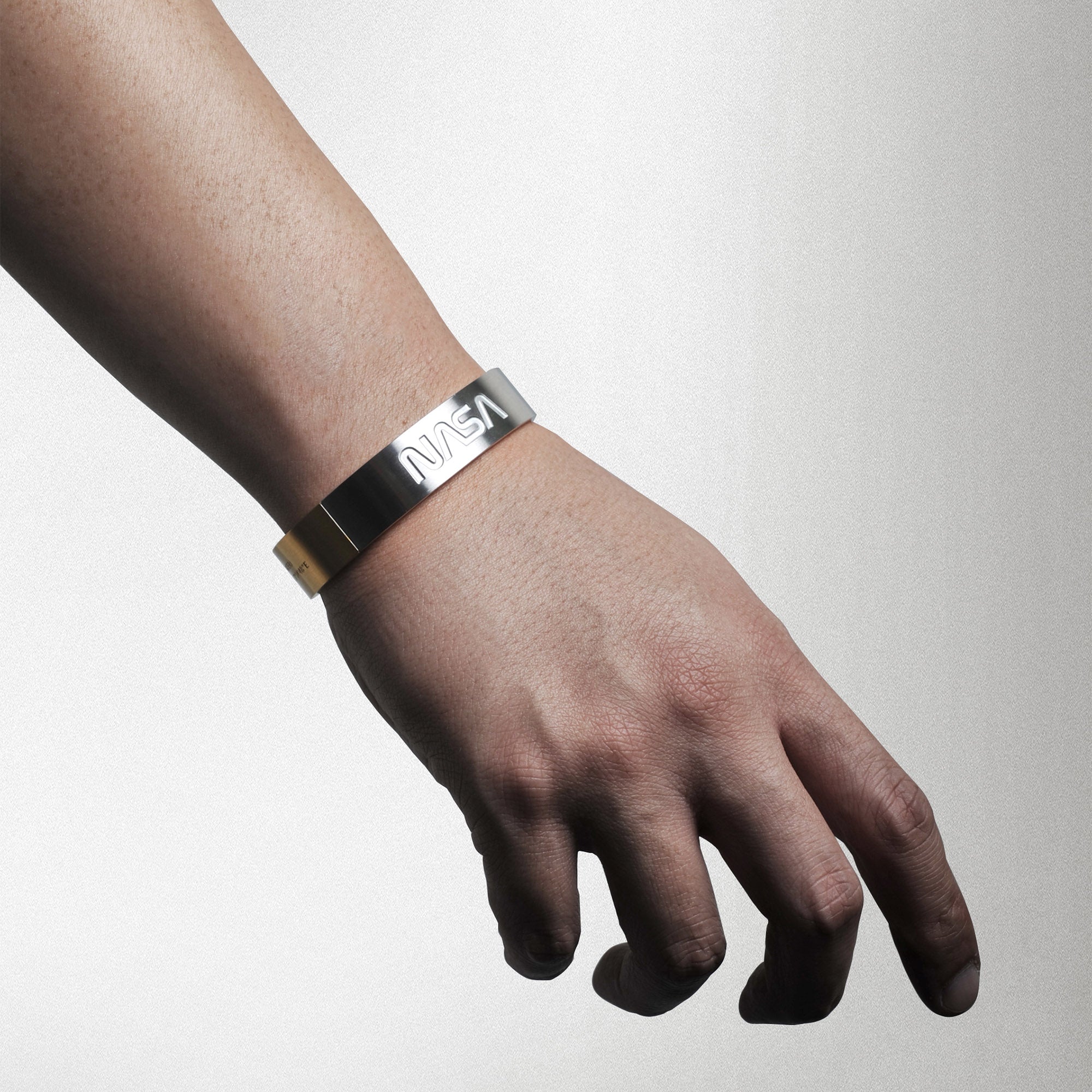 Futuristic elegance. A slip-on gold/silver or blue/silver duo-colored stainless steel bracelet with the landing coordinates and NASA logo embossed. A collaboration with Shannnam.